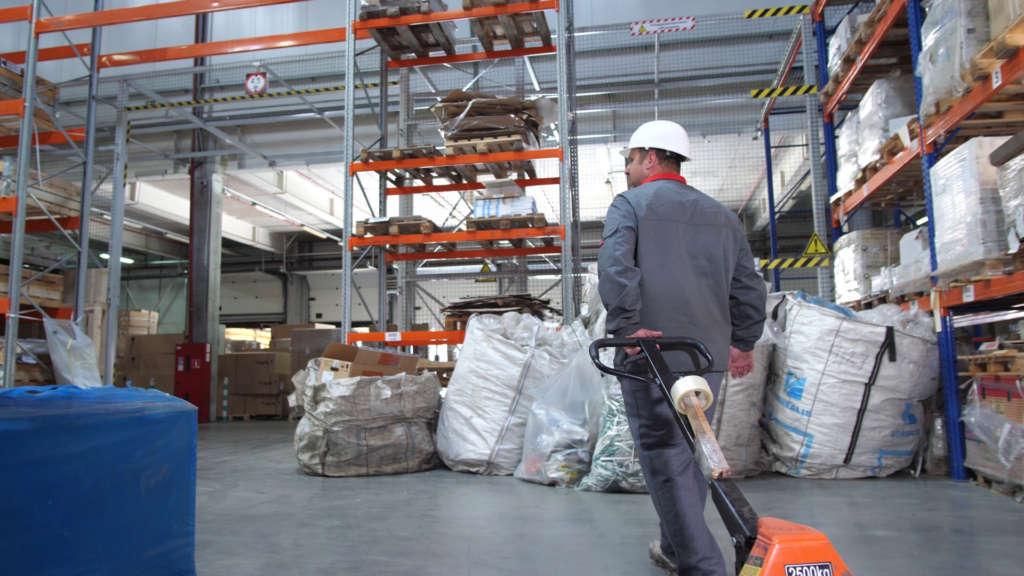 Warehouse associate moving a pallet with a pallet jack, highlighting the role of fair labor standards and employee morale in daily warehouse operations.